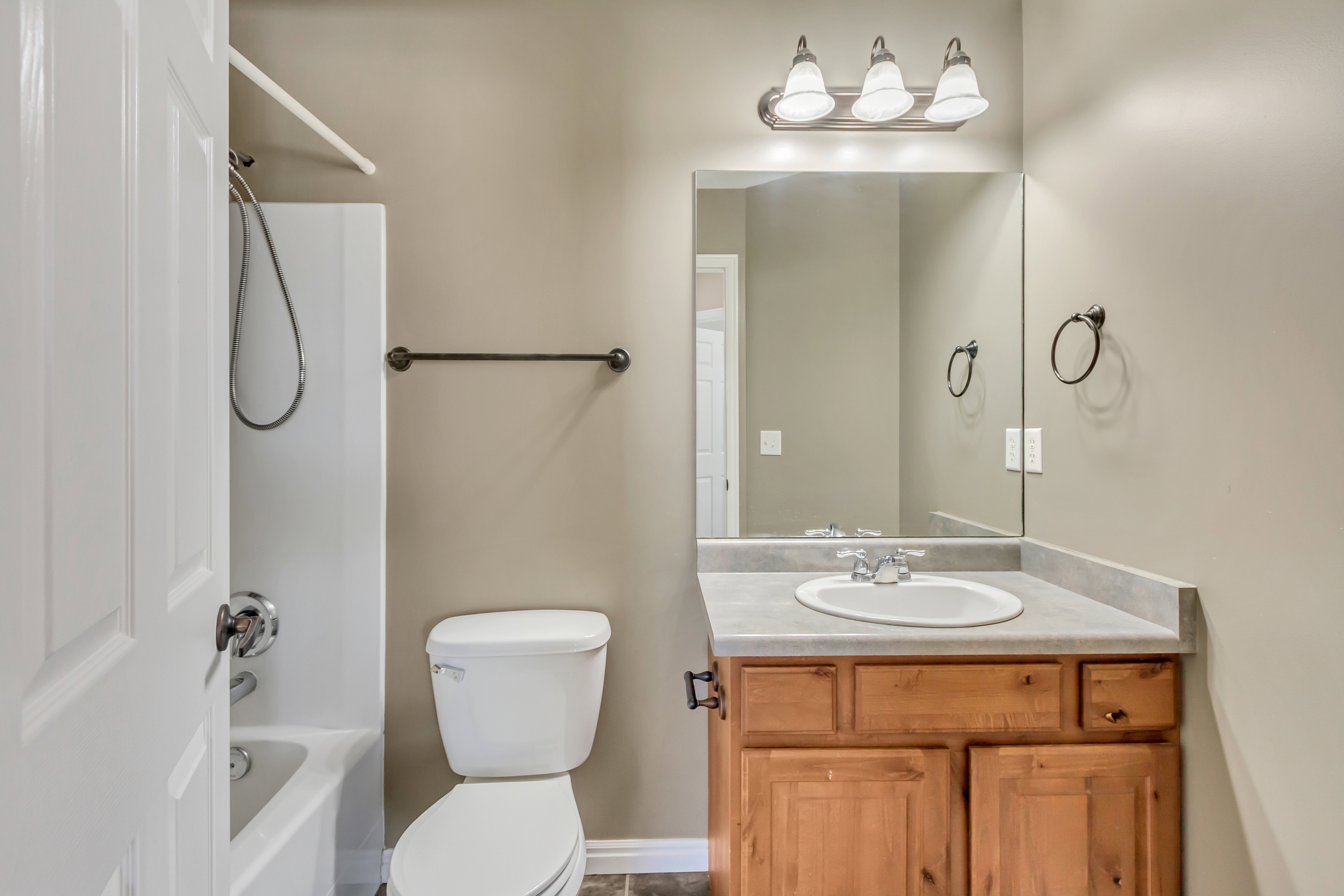 Bathroom featuring a vanity with a light wood-finish cabinet, integrated sink, and a large mirror