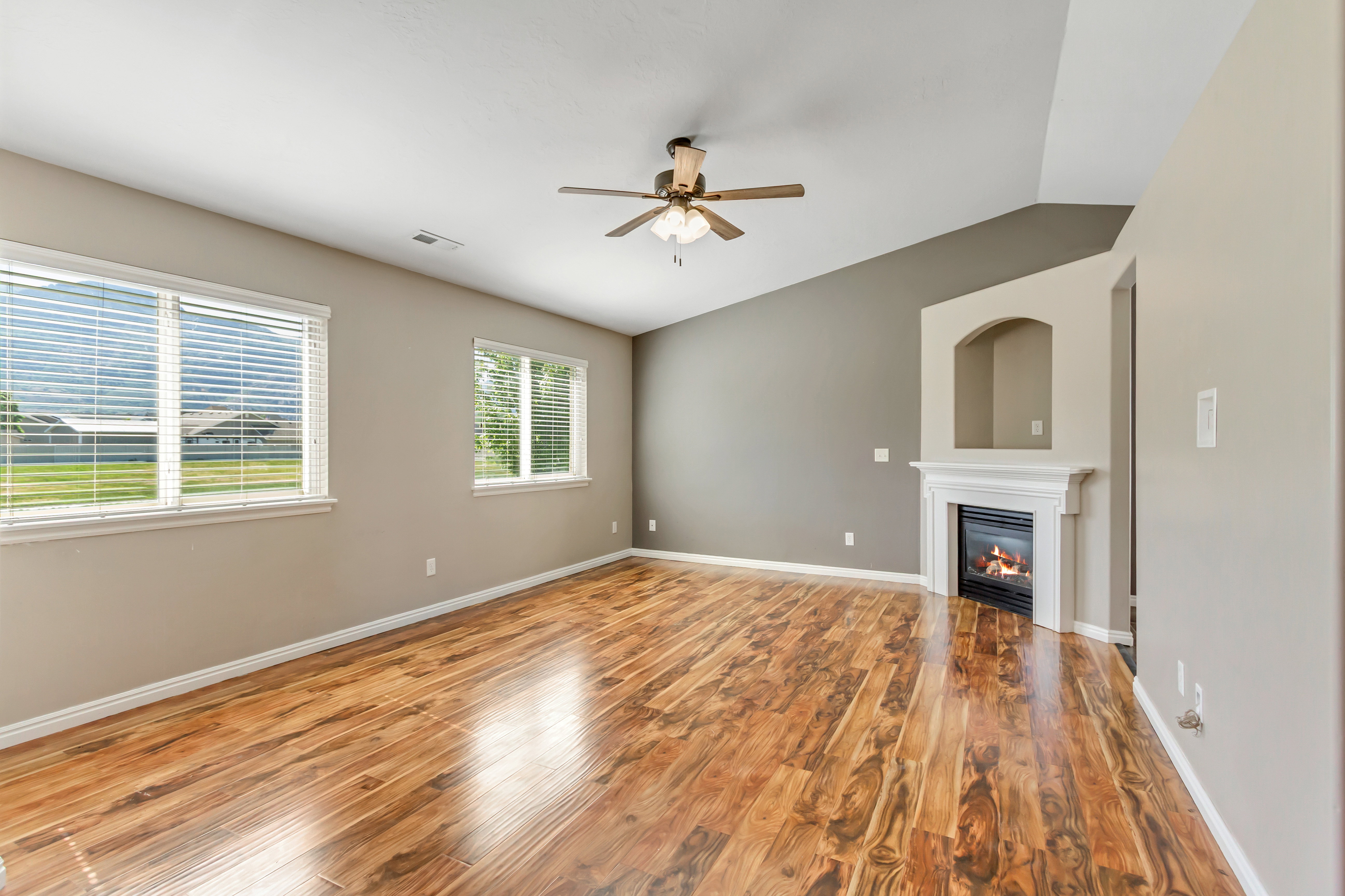 Spacious interior with wood-finish flooring, a vaulted ceiling, and a ceiling fan