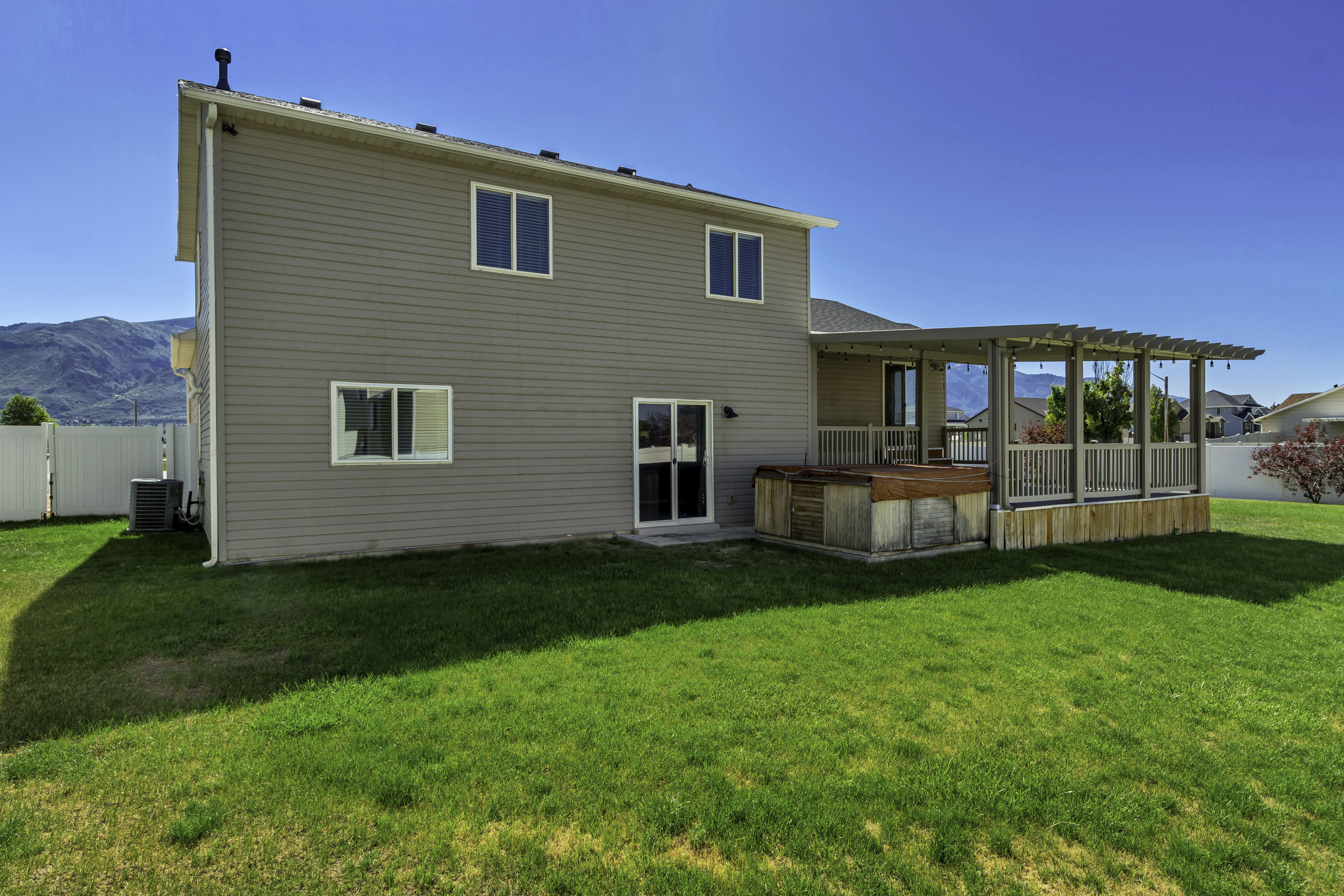Expansive green lawn with a two-story exterior featuring tan siding