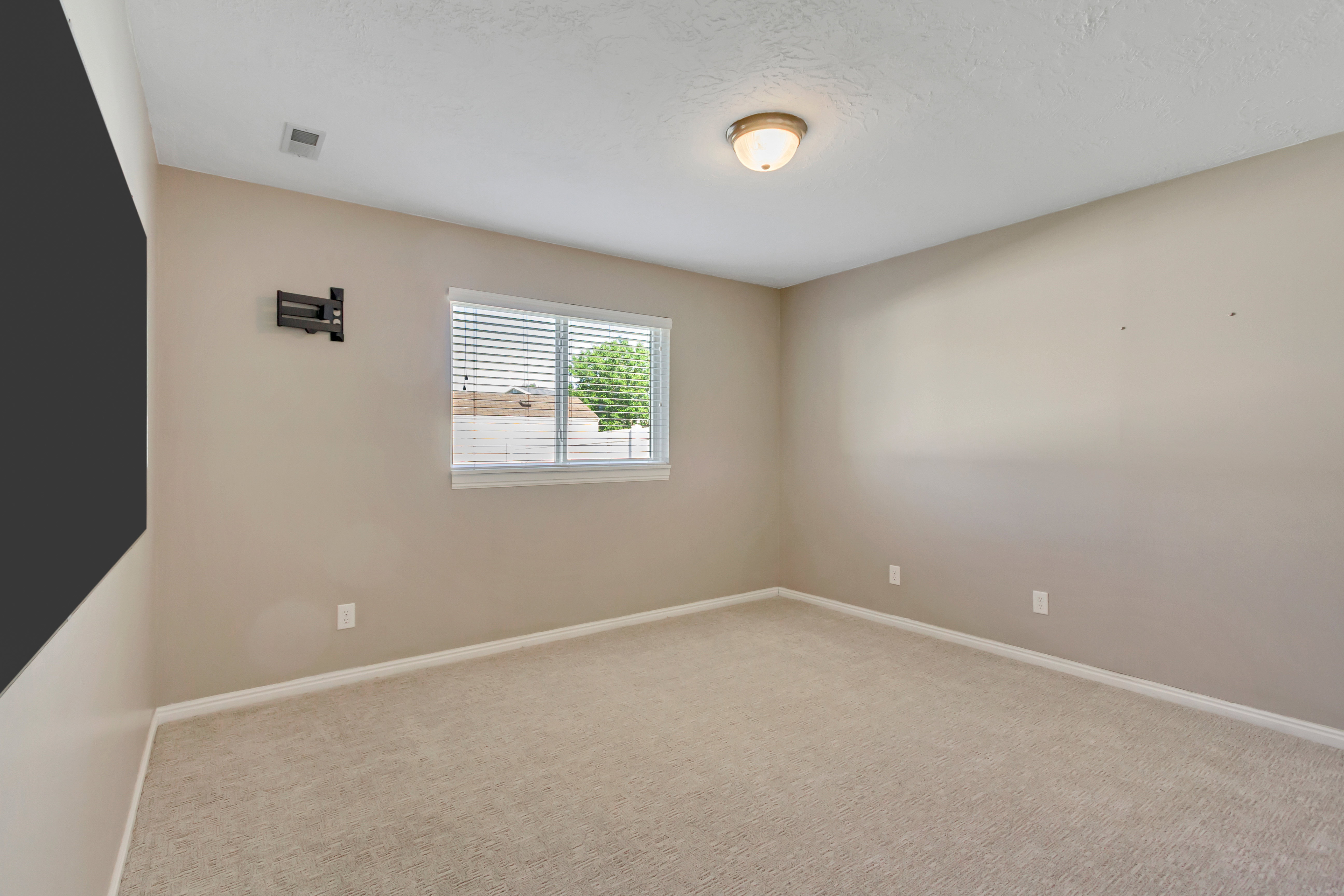 Carpeted room with neutral wall tones and a window featuring blinds