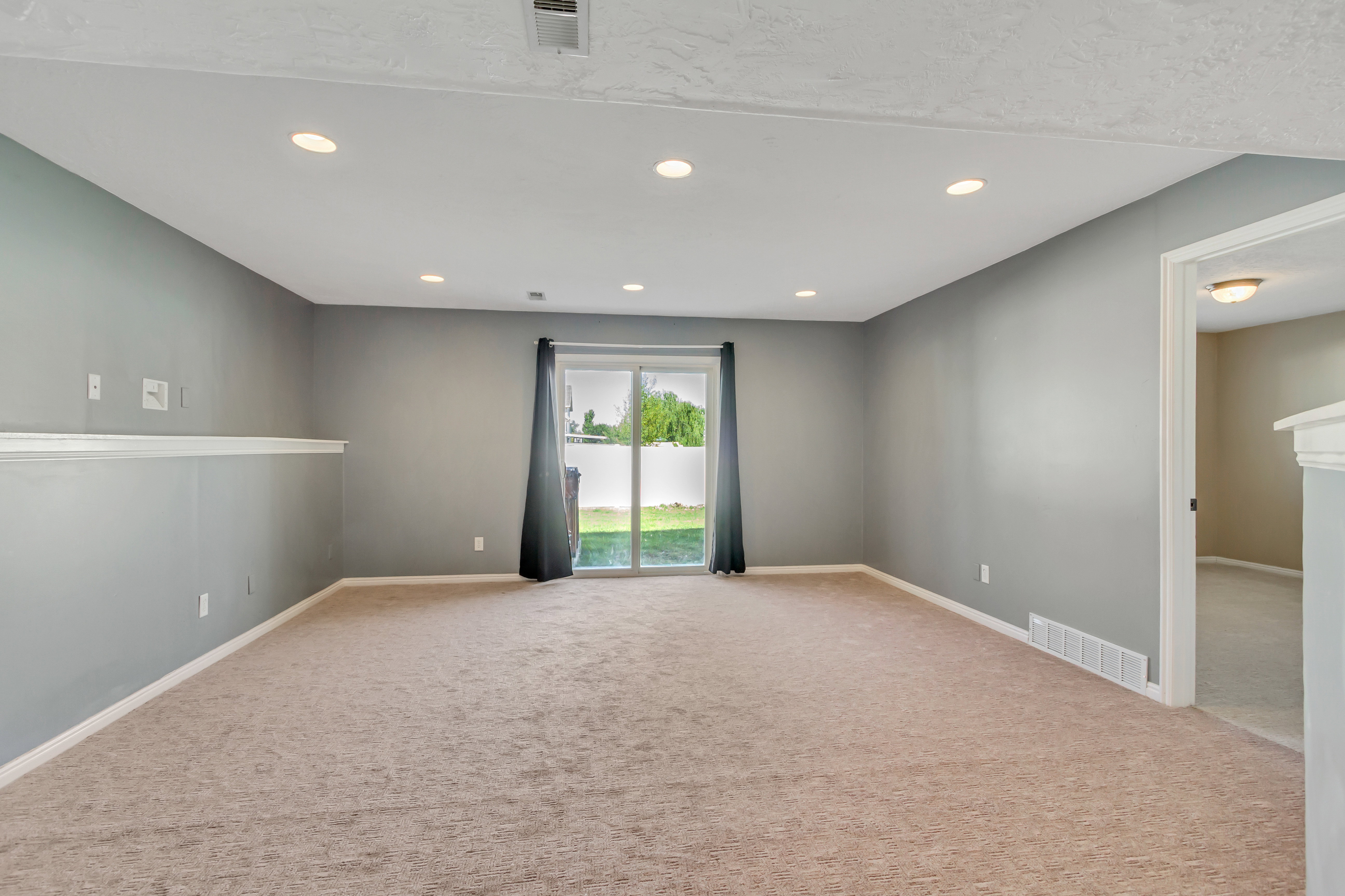 Carpeted room featuring recessed lighting, gray painted walls, white baseboards, and a glass sliding door providing access to the outdoors