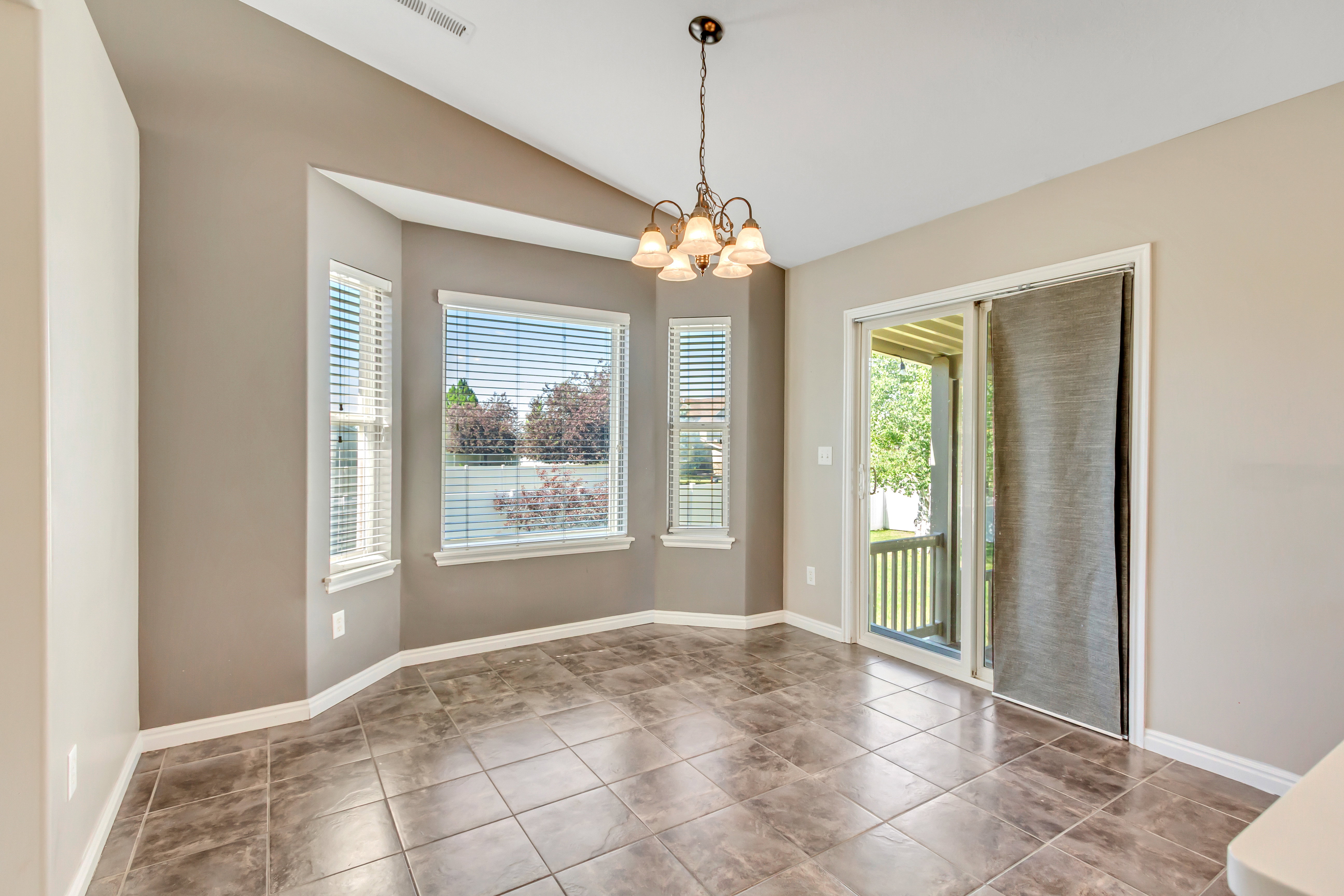 Dining area featuring a bay window with multiple panes, a glass sliding door, vaulted ceilings, and tile flooring