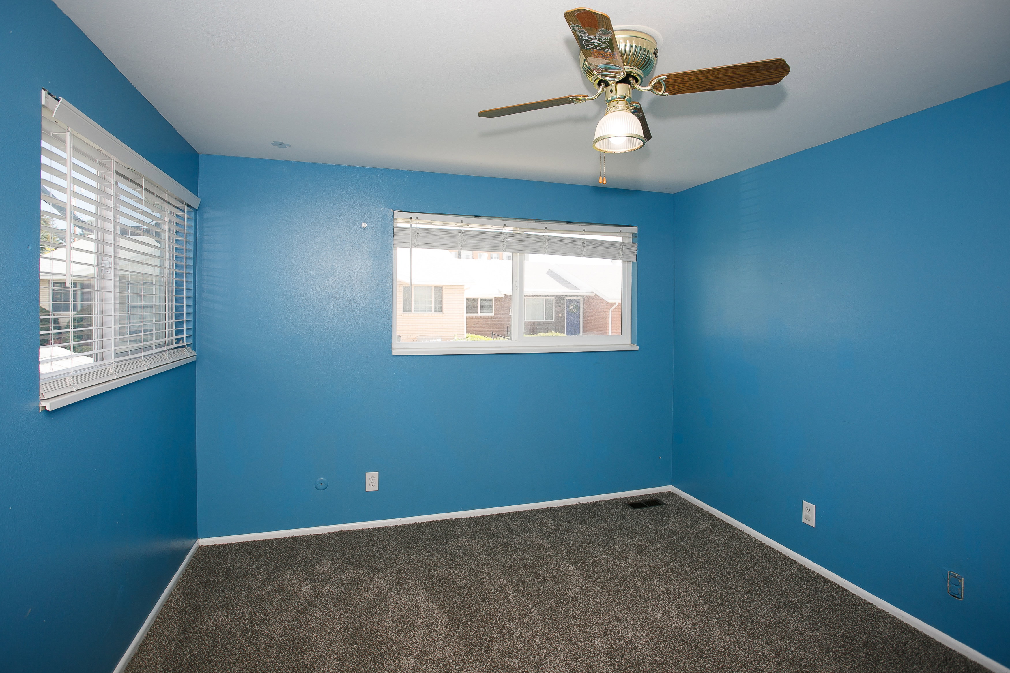 Room featuring two windows with horizontal blinds, a ceiling fan with light fixture, and wall-to-wall carpeting