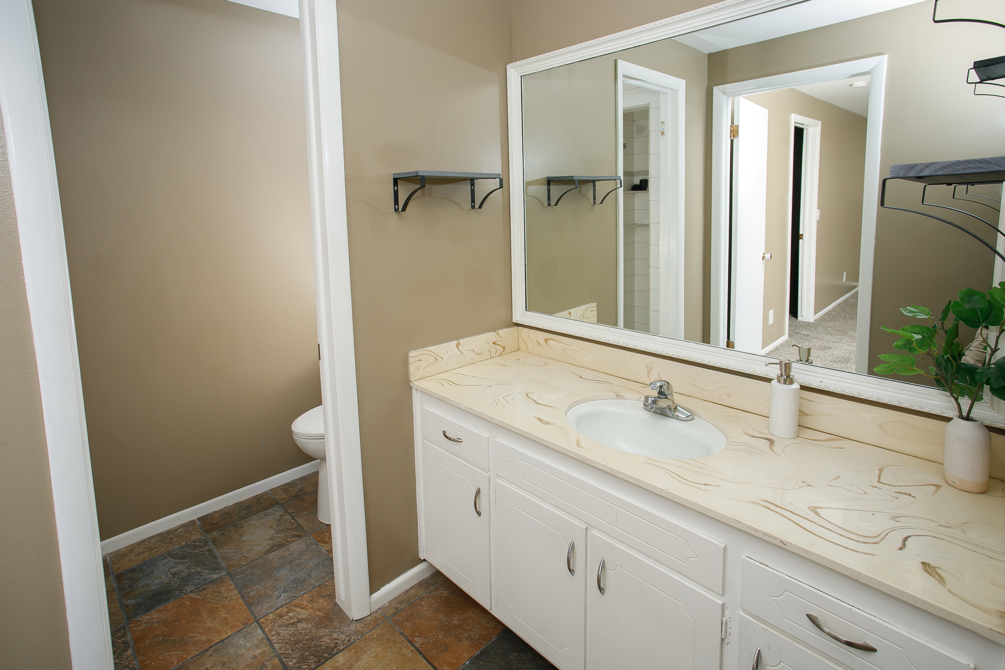Bathroom vanity featuring a white cabinet base, light-toned countertop with distinct veining, and an integrated oval sink