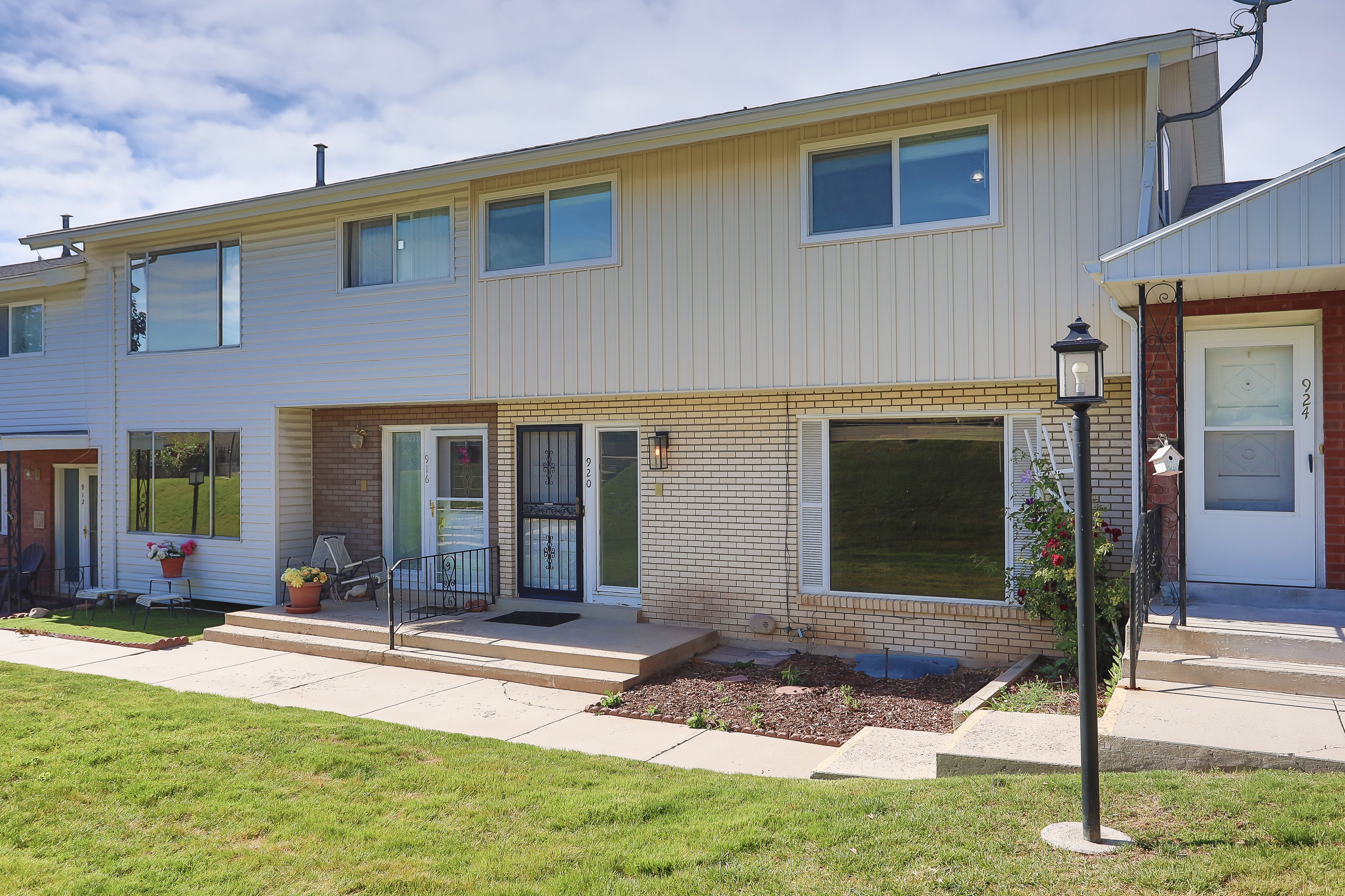 Exterior featuring a combination of light brick and vertical siding, multiple windows, and a concrete walkway leading to the front entry