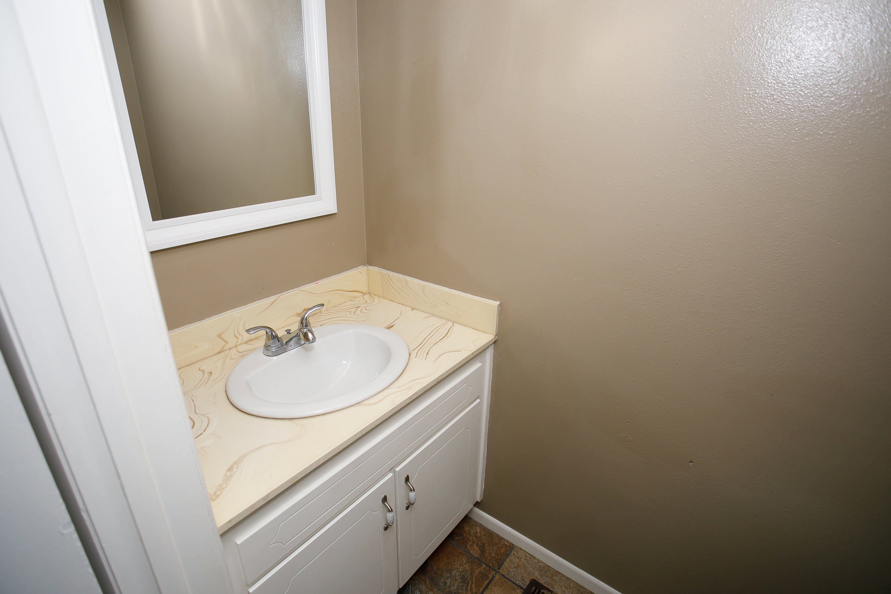 White vanity with dual cabinet doors, an undermount sink, and a patterned countertop
