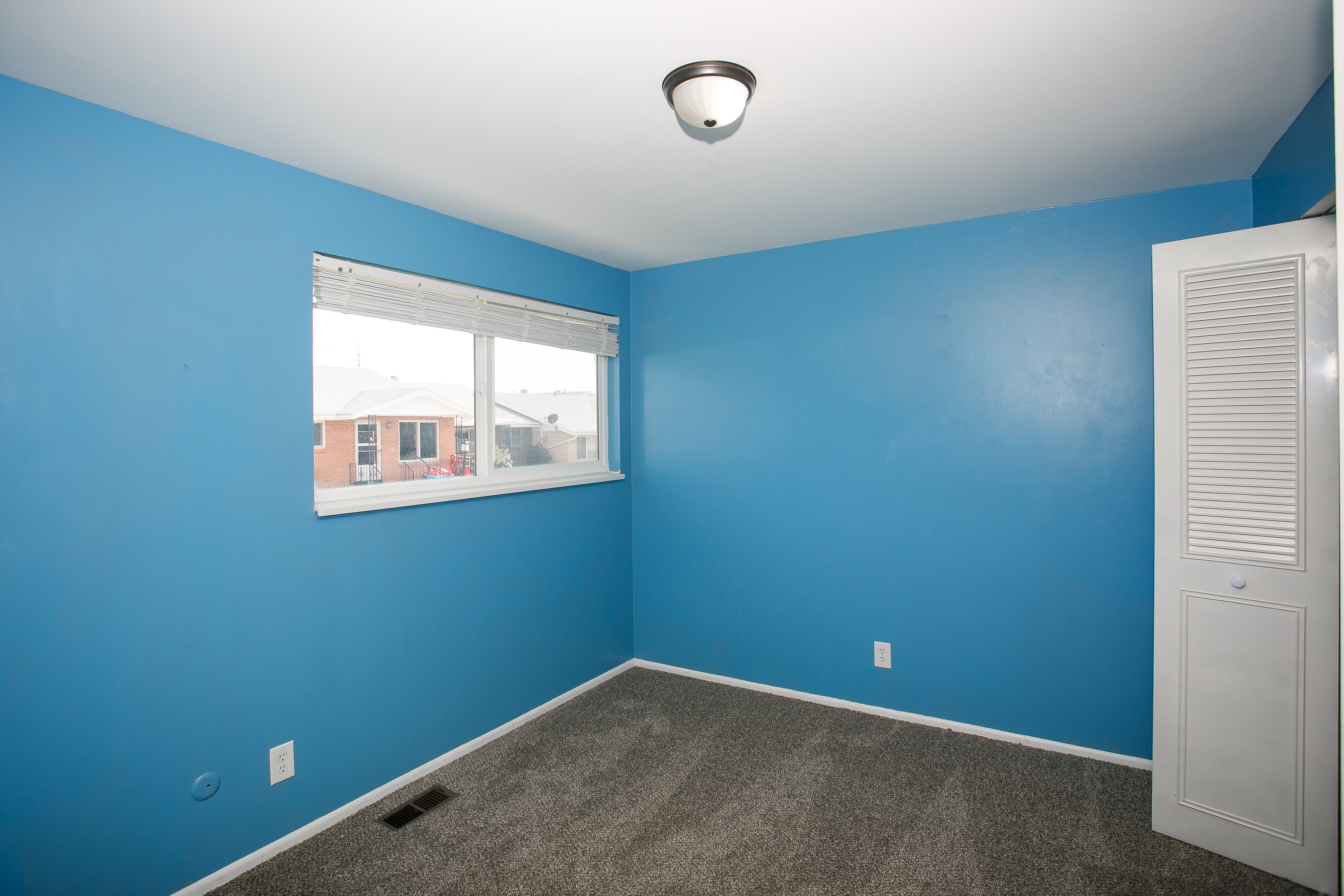 Wall-to-wall carpeting and a ceiling-mounted light fixture define this room