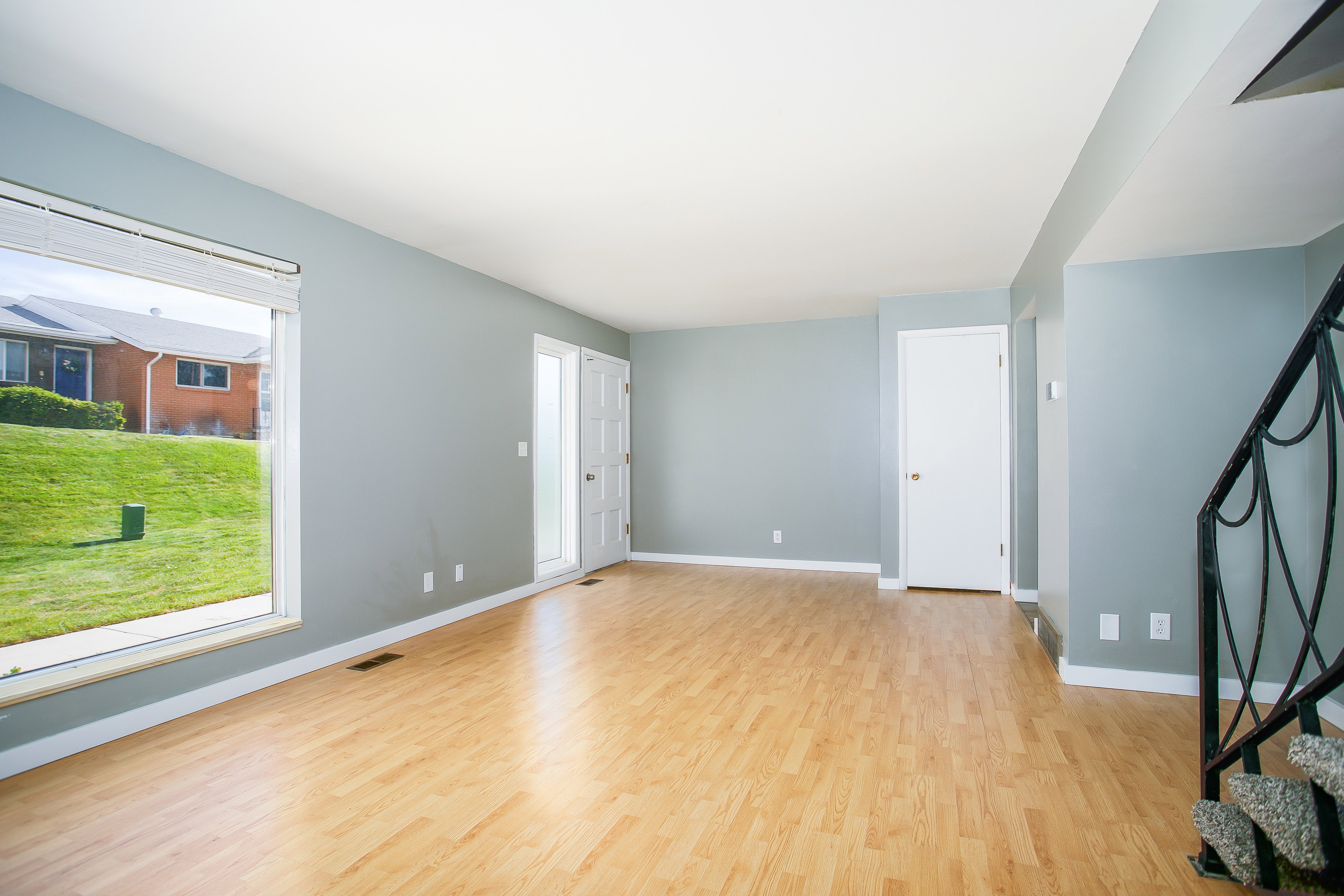 Spacious interior featuring wood-finish flooring, light grey wall paint, and white baseboards