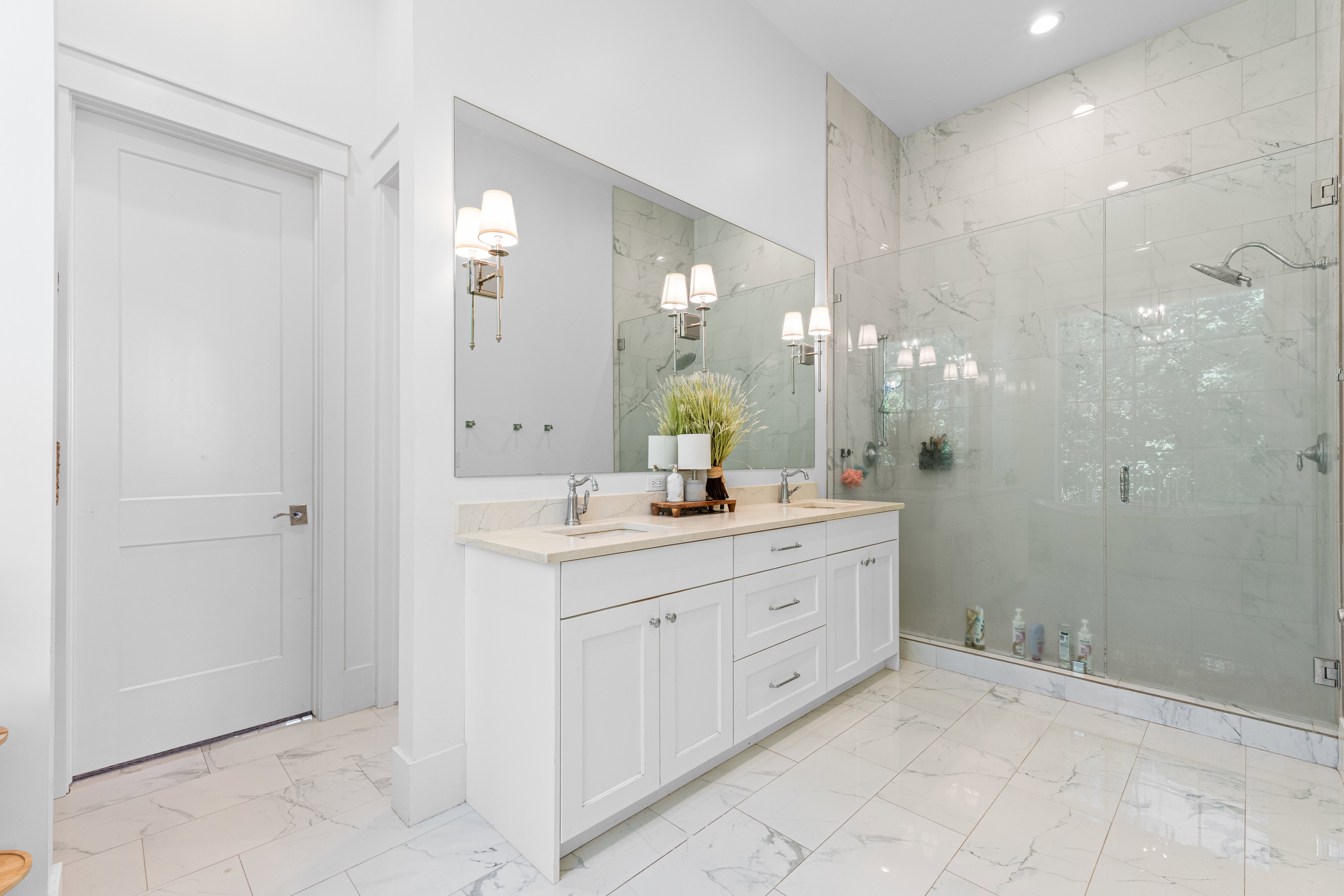 White marble-look tile flooring with a dual vanity featuring light-colored countertops, undermount sinks, and brushed nickel fixtures