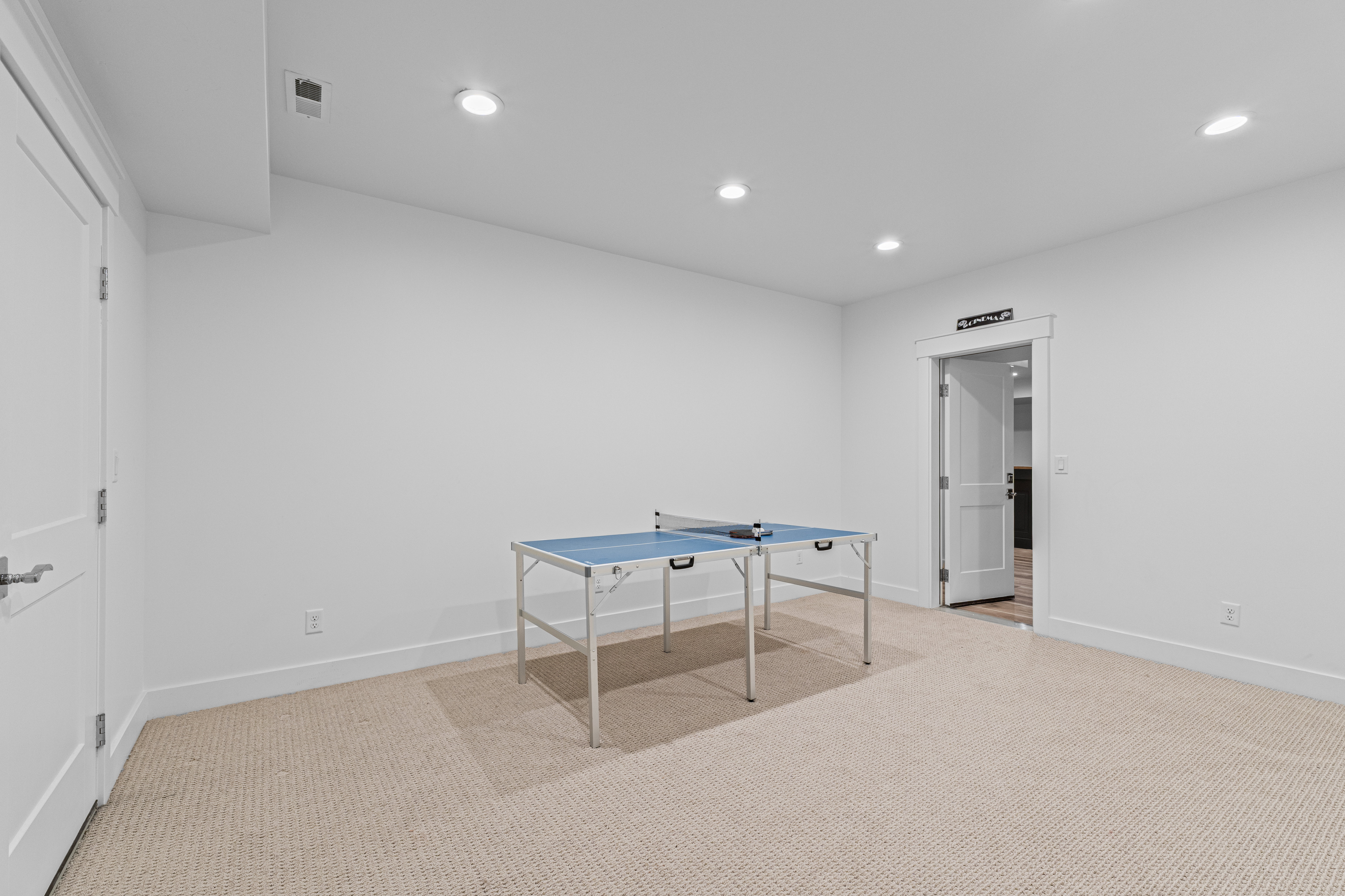 Carpeted recreation room featuring white walls, recessed lighting, and white trim