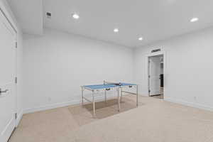 Carpeted recreation room featuring white walls, recessed lighting, and white trim