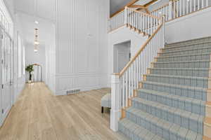 Grand entrance featuring a custom staircase with carpeted treads and a light wood railing