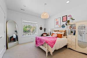 Bright room featuring white walls, textured carpeting, a large window with white trim, and a woven pendant light fixture
