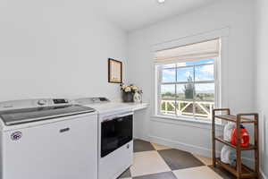 Laundry area featuring a checkered tile floor, a window with a Roman shade, and a built-in countertop