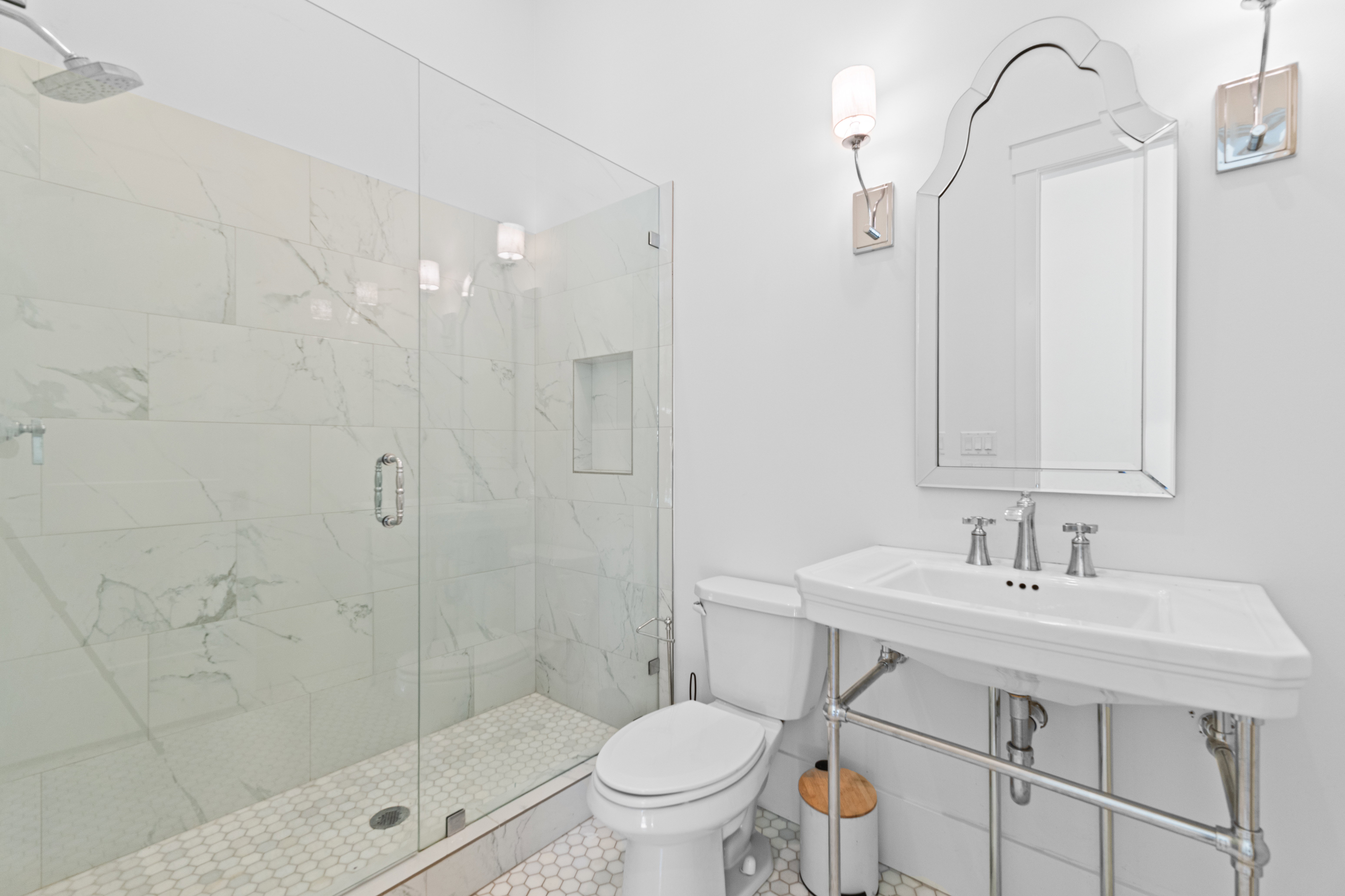 Bathroom featuring a glass-enclosed shower with white marble-look tile, a built-in shower niche, and a rain showerhead