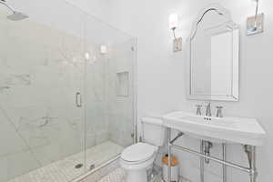 Bathroom featuring a glass-enclosed shower with white marble-look tile, a built-in shower niche, and a rain showerhead