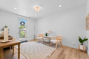 Bright interior room featuring a glass-paneled door, wood-finish flooring, recessed lighting, and a decorative ceiling fixture