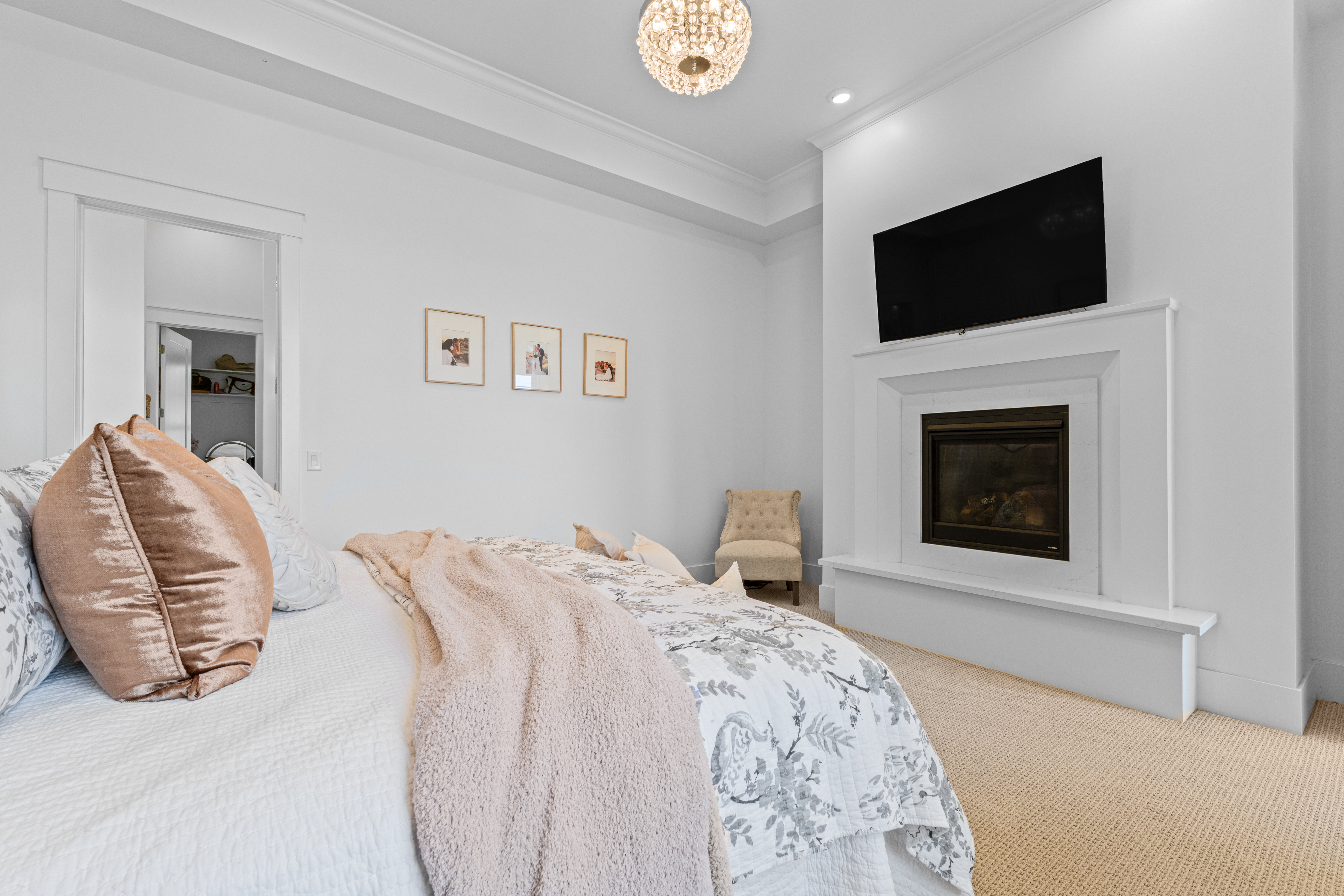 Recessed fireplace with a framed mantel and hearth, tray ceiling with crown molding, and a chandelier-style light fixture