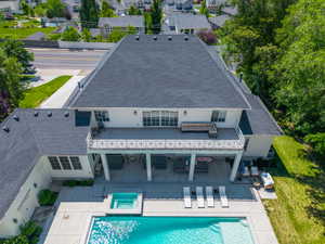 Expansive rear exterior featuring a substantial patio, integrated swimming pool with spa, covered terrace, and a second-story balcony