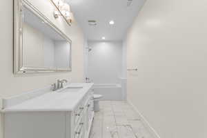 White vanity with a single basin, brushed nickel faucet, and a large framed mirror with sconce lighting