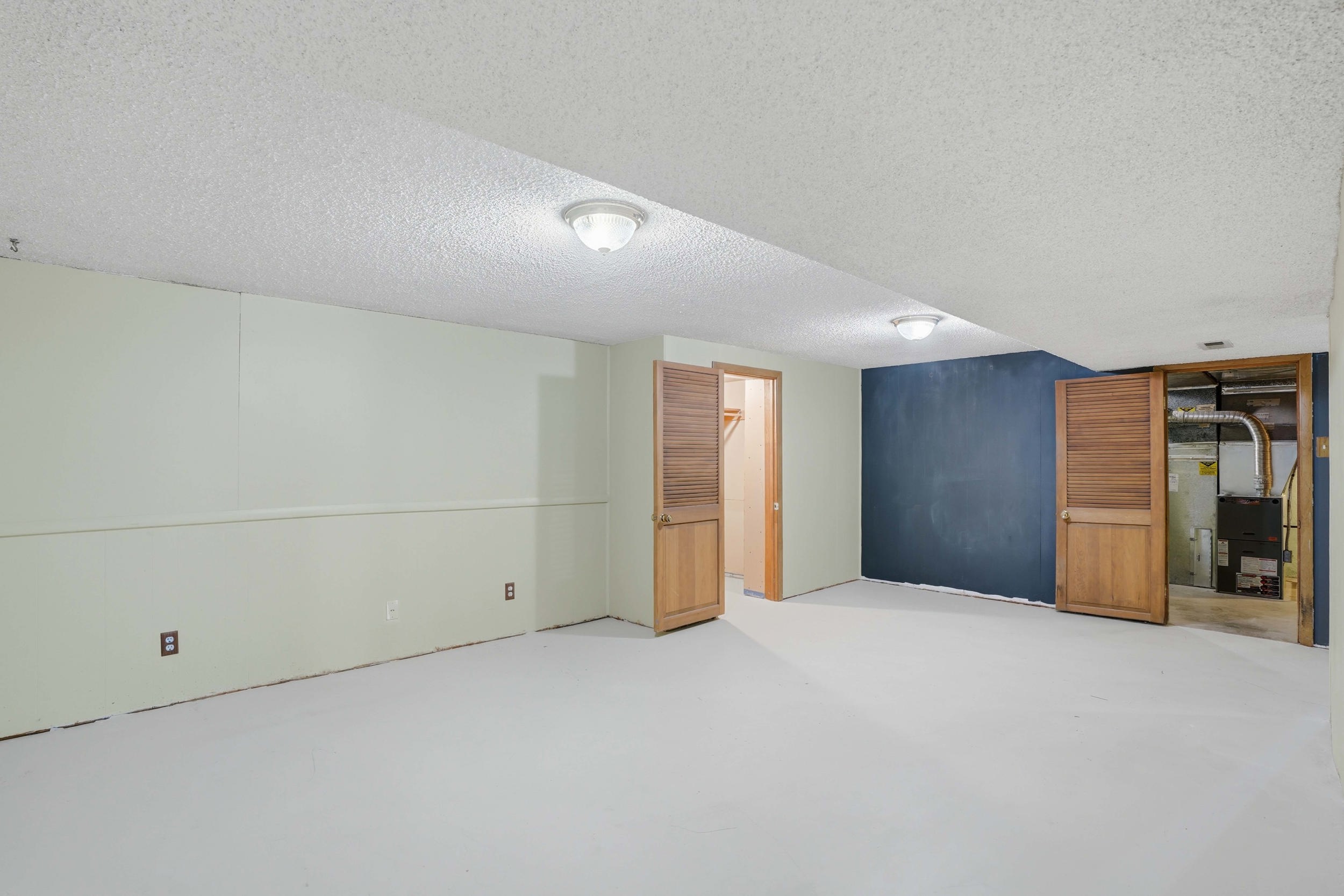Lower level space featuring light-colored flooring, painted walls, and ceiling-mounted lighting fixtures