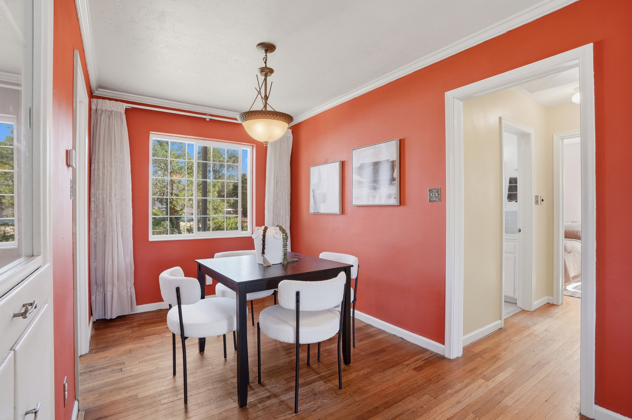 Dining area featuring hardwood flooring, a multi-pane window, and a decorative ceiling light fixture