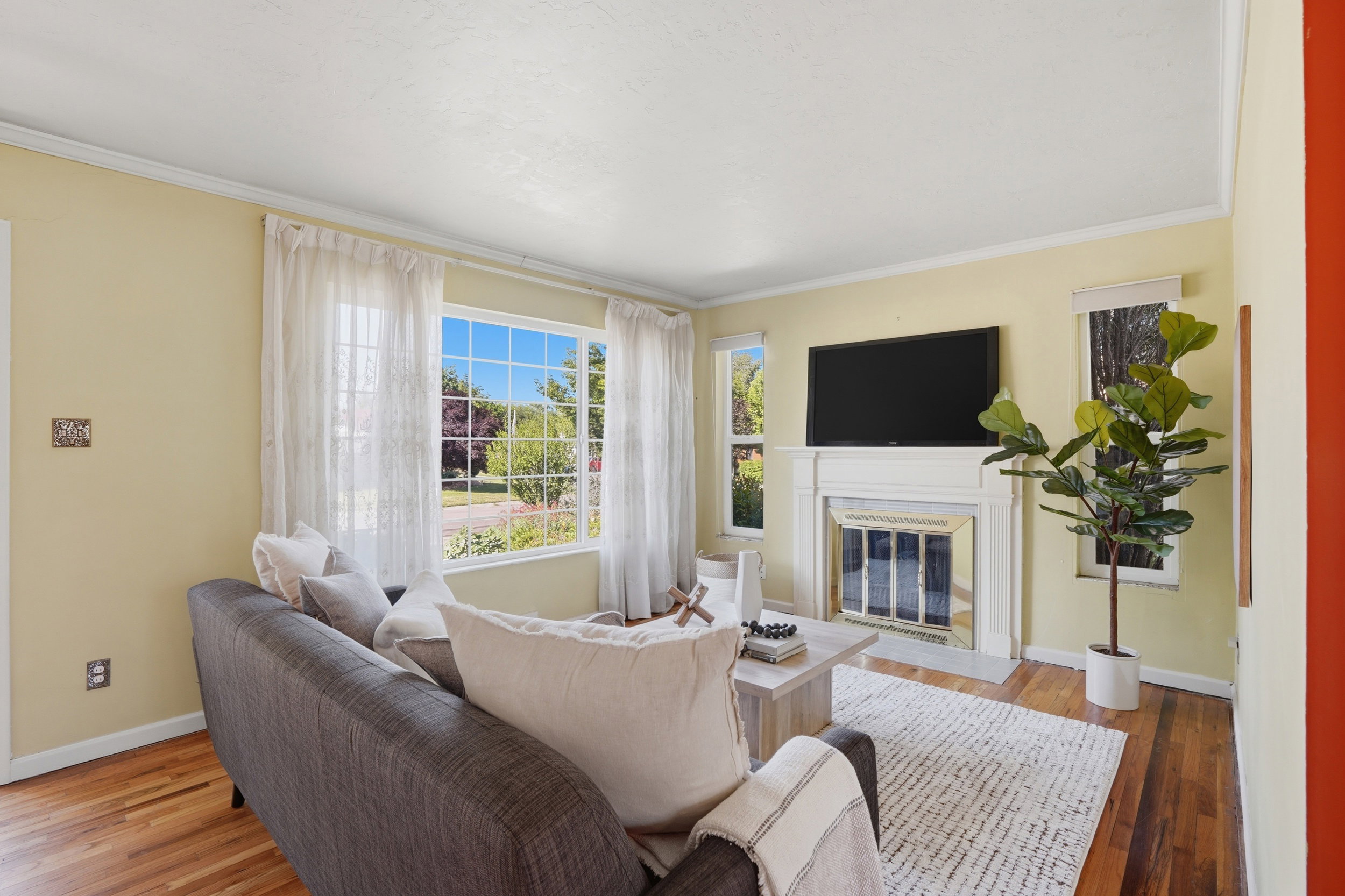 Living area featuring a white mantel fireplace, multiple windows, and wood-finish flooring