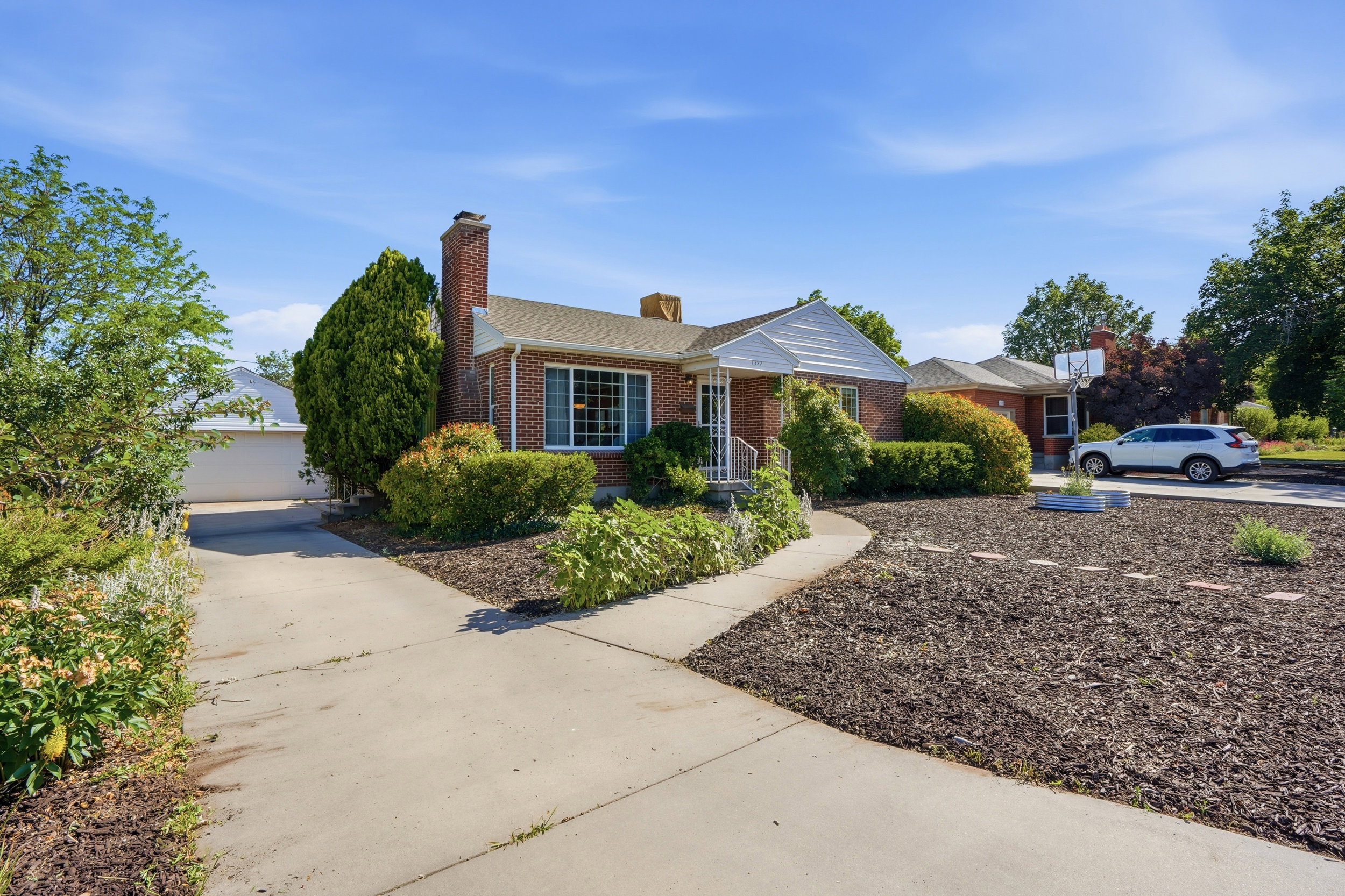 Brick exterior with white trim, featuring a concrete driveway and walkway