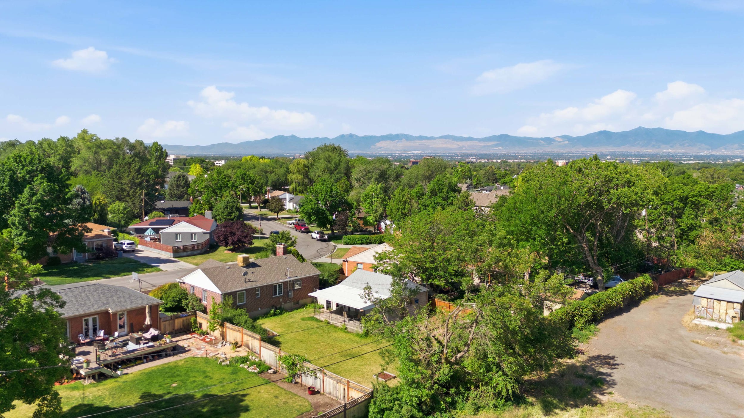 Residential neighborhood featuring mature trees and a clear mountain range in the distance
