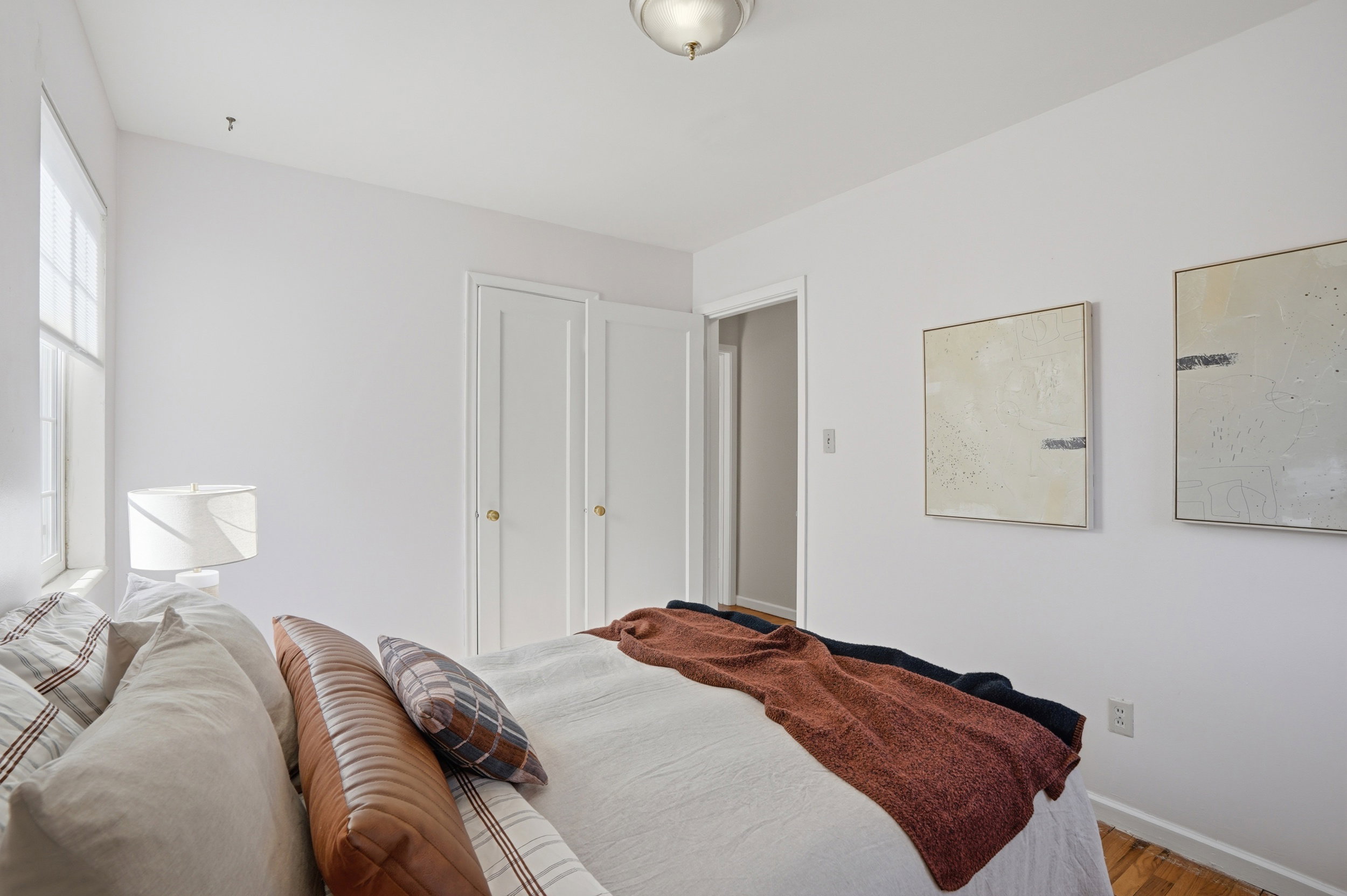 Bedroom featuring white walls, light wood-finish flooring, and a window with natural light