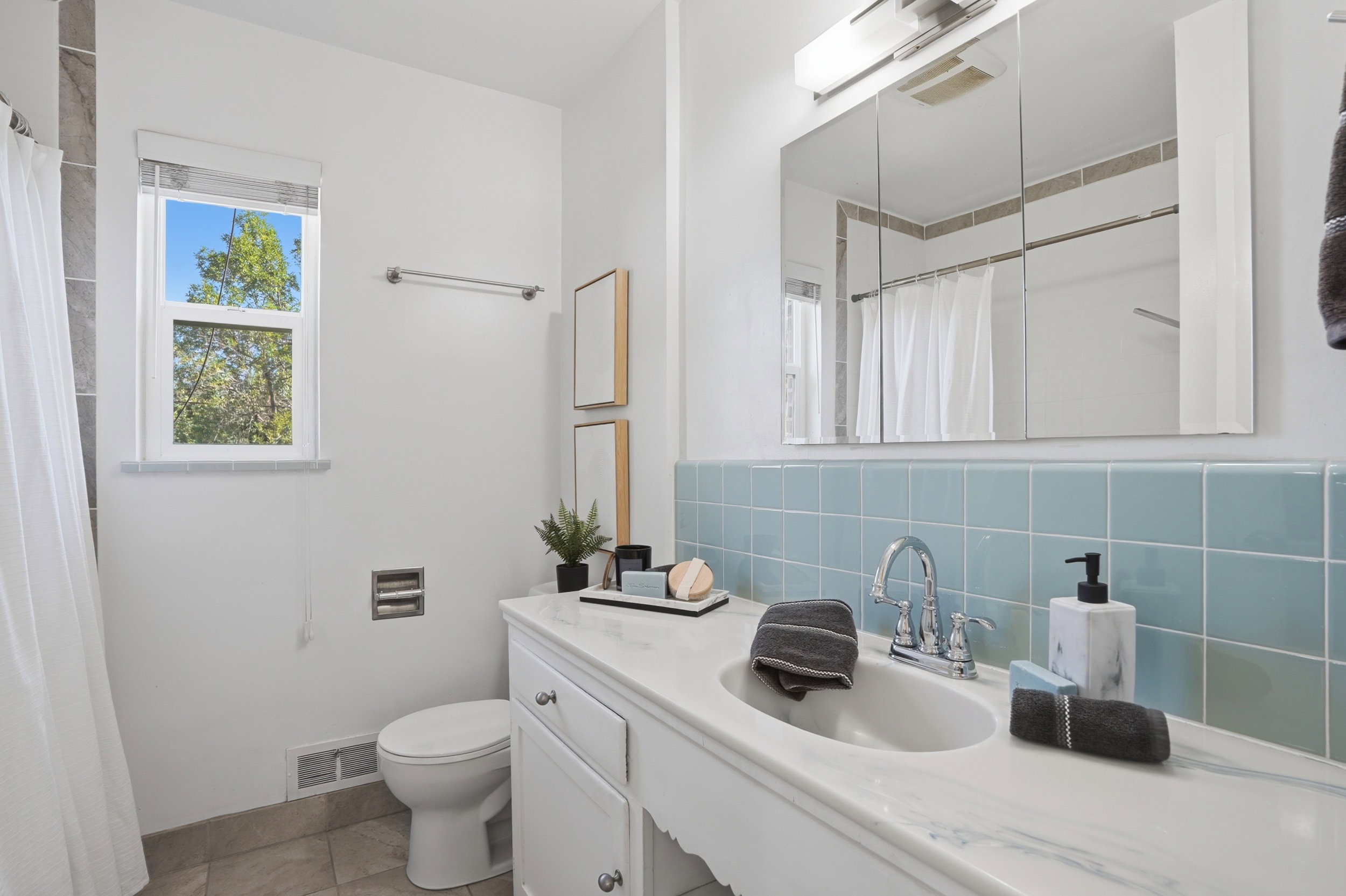 Bathroom featuring a white vanity with an integrated sink, a large mirrored medicine cabinet, and a tiled backsplash