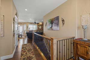 Interior hallway featuring wood-finish flooring, recessed lighting, and a stairway with wood newel posts and black iron balusters