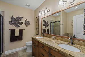 Bathroom vanity with dual undermount sinks, granite countertop, and wood-finish cabinetry