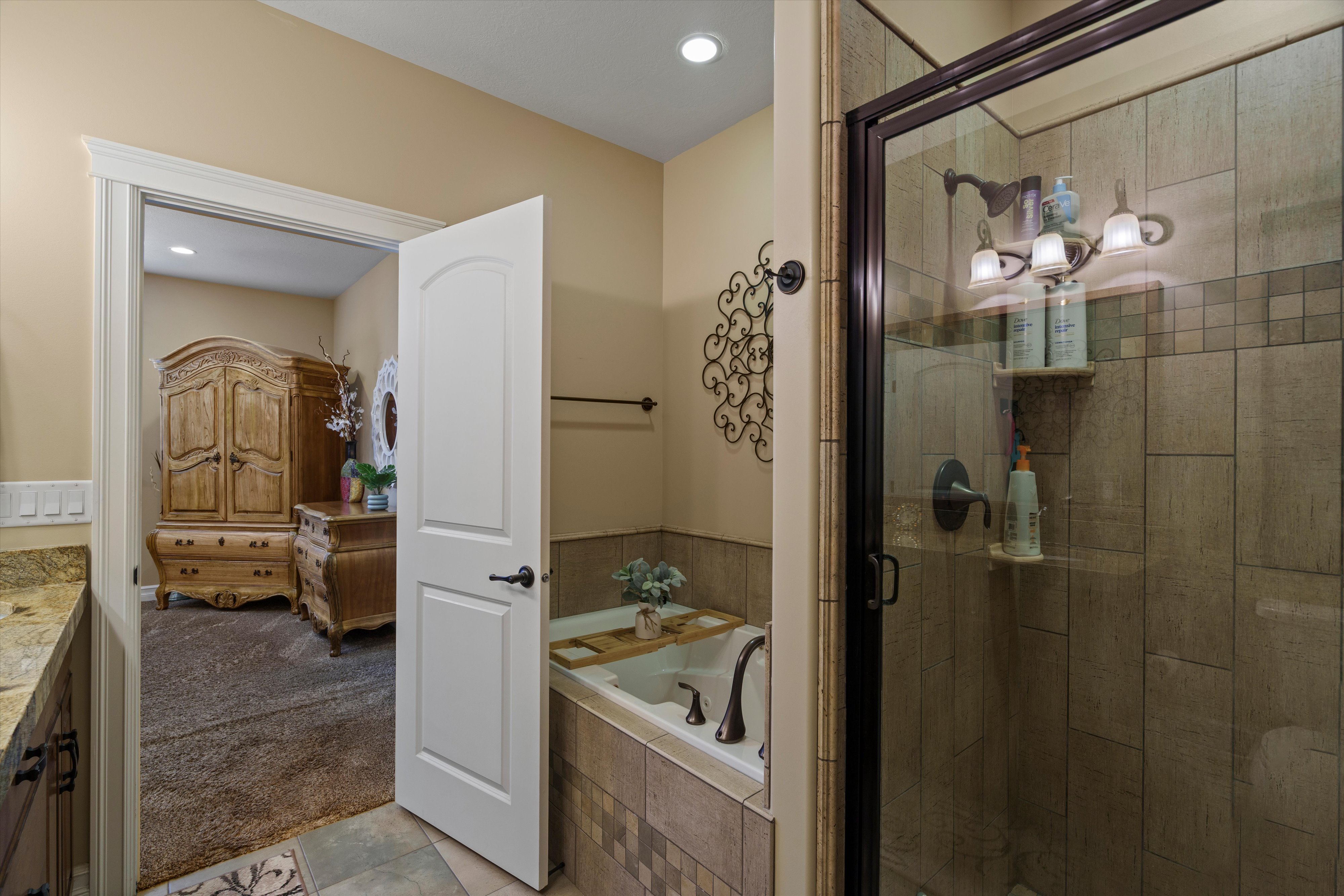 Full-size walk-in shower with glass enclosure, tiled walls, and three-bulb vanity lighting