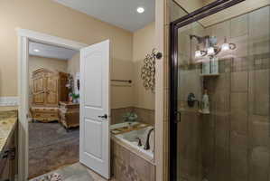 Full-size walk-in shower with glass enclosure, tiled walls, and three-bulb vanity lighting