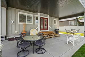 Expansive covered patio featuring a concrete surface, a wood-finish ceiling, and direct access to the interior via double red doors with glass inserts
