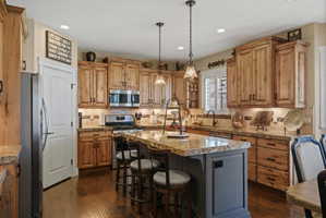 Gourmet kitchen featuring wood-finish cabinetry, stainless steel appliances, and a central island with bar seating
