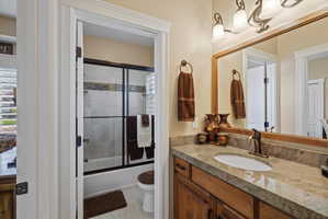 Bathroom featuring a built-in vanity with a stone countertop, an undermount sink, and a framed mirror