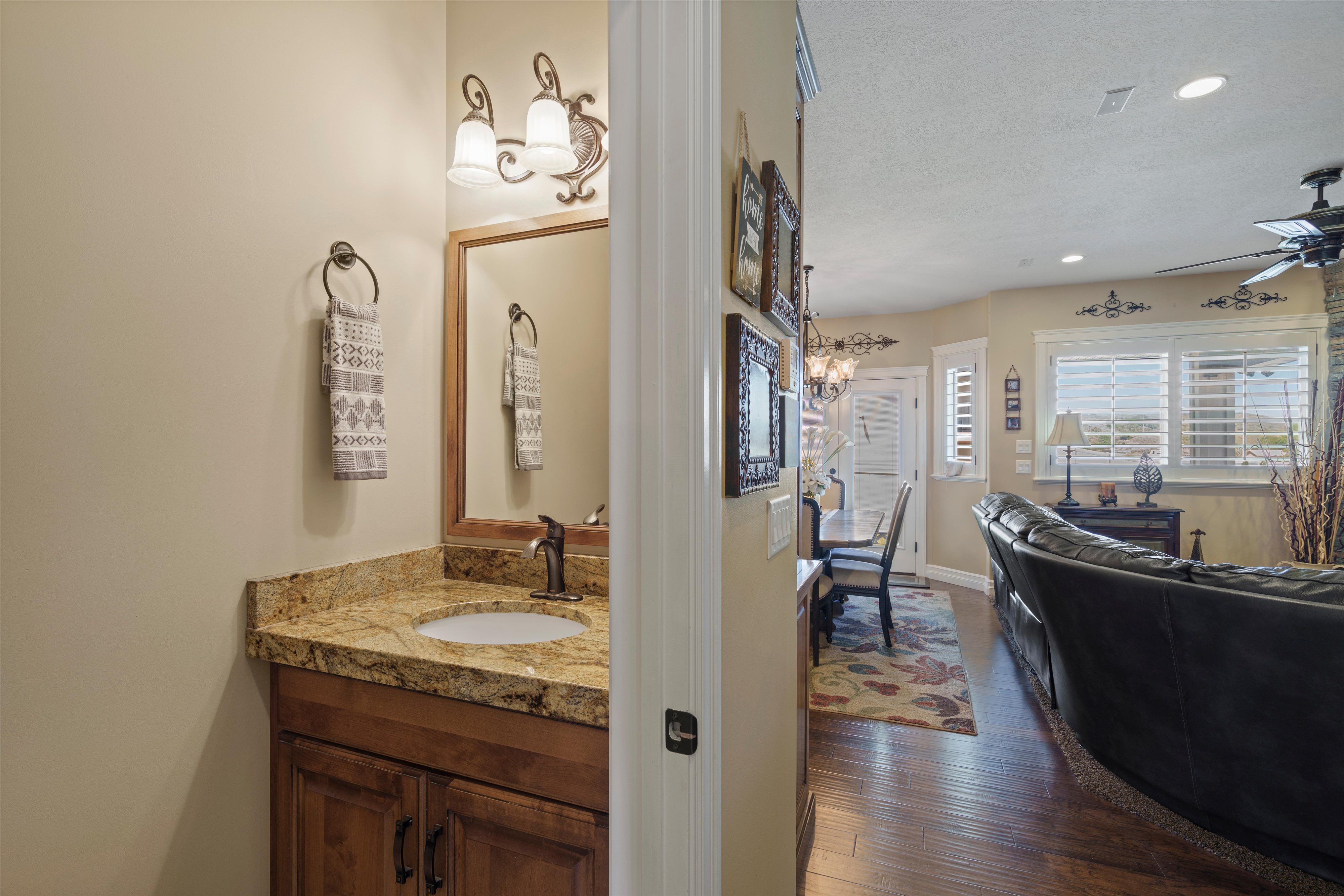 Powder room featuring a wood vanity with a granite countertop, undermount sink, and bronze-finish faucet