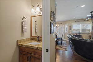 Powder room featuring a wood vanity with a granite countertop, undermount sink, and bronze-finish faucet