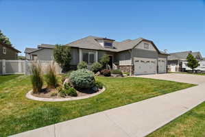 Craftsman-style home featuring vertical siding, stone accents, and a multi-car garage with white paneled doors