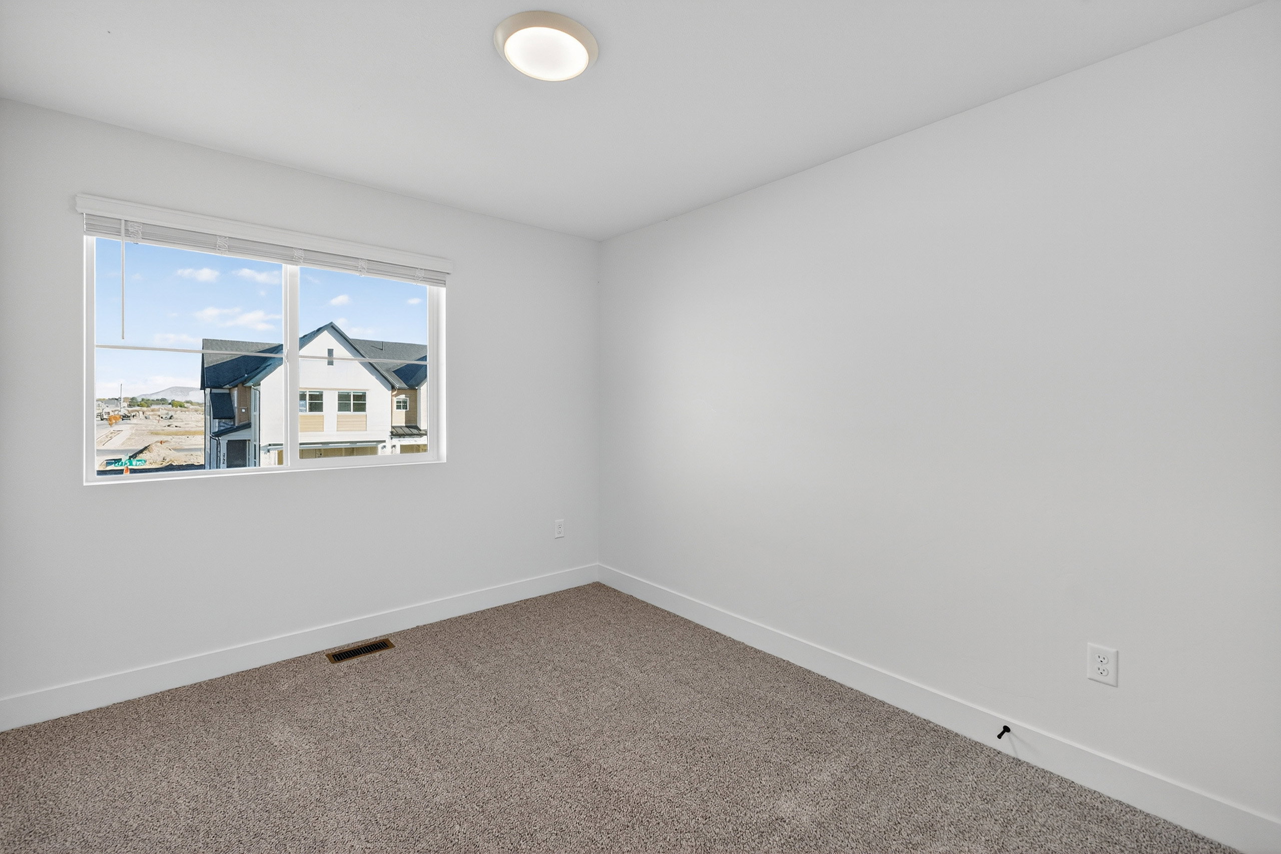 Bright room featuring a large window, carpeted flooring, white baseboards, a flush-mount ceiling light, and neutral wall paint