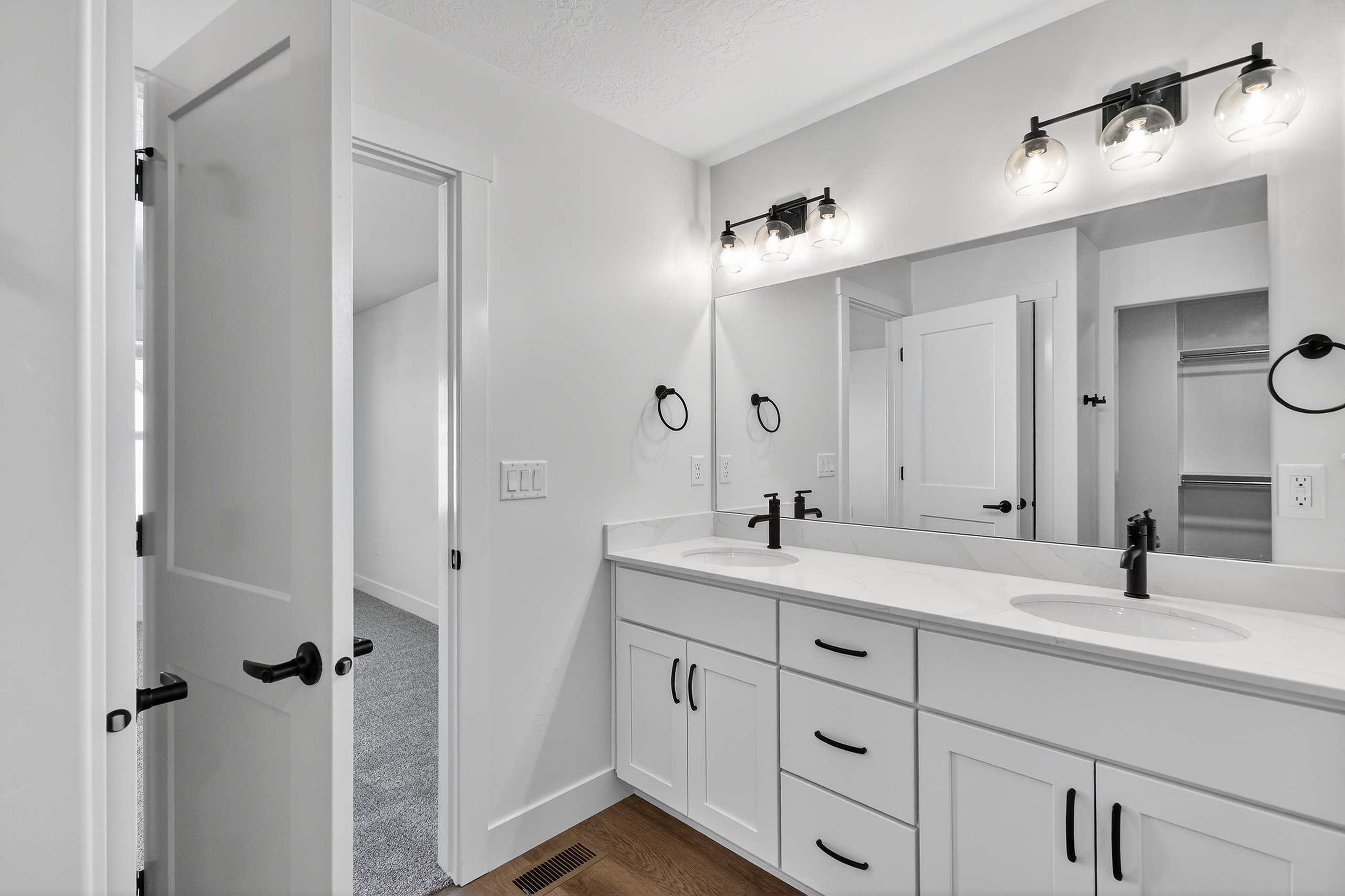 Double vanity featuring white cabinetry, integrated sinks, and black hardware