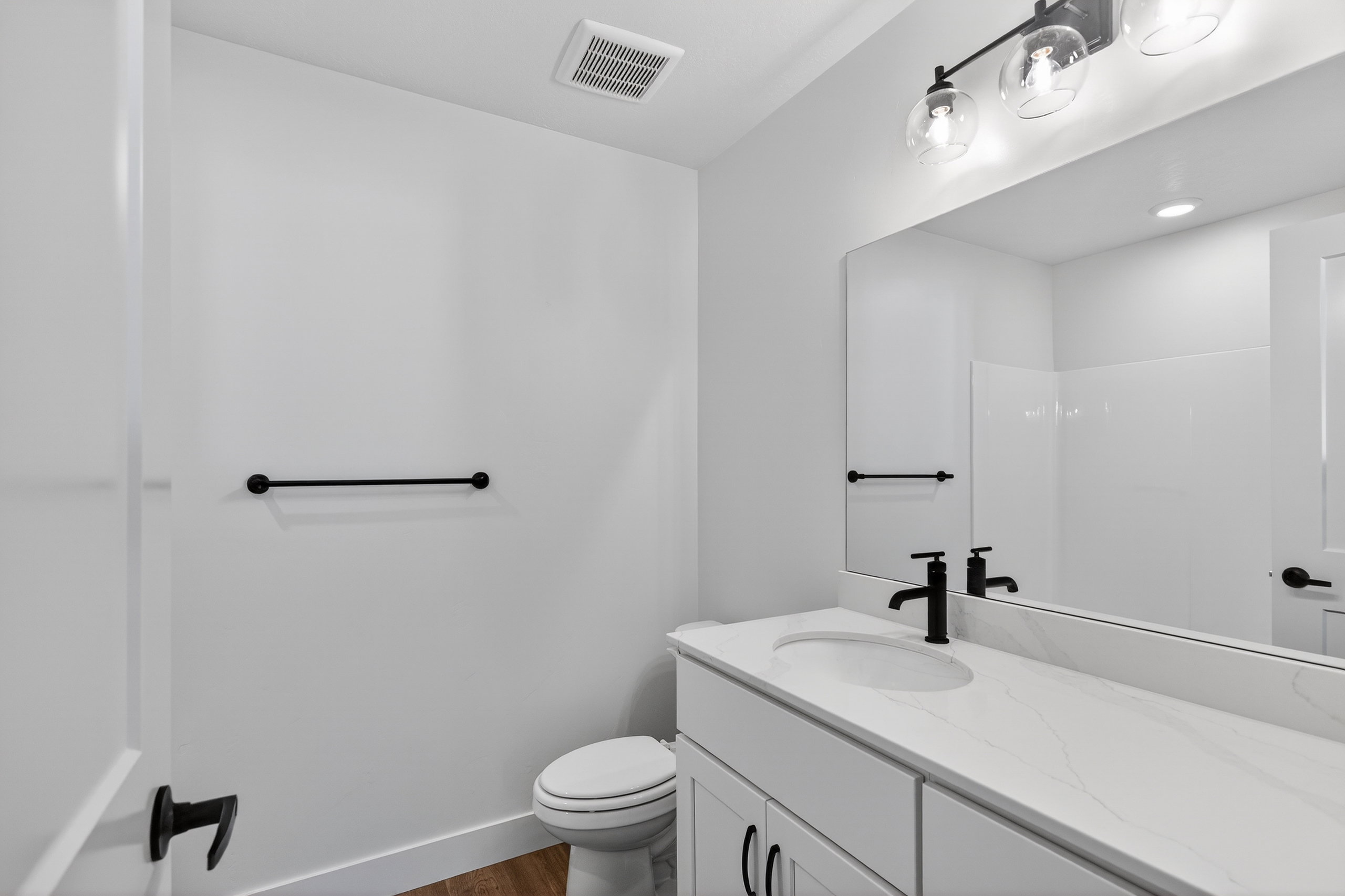 Bathroom vanity featuring a quartz countertop, integrated sink, and matte black faucet