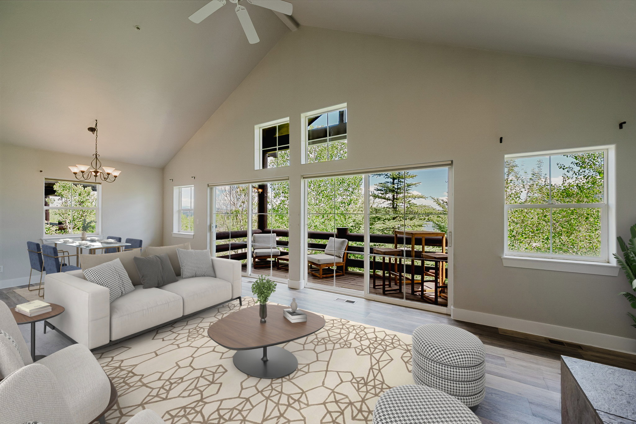 Spacious living area featuring a vaulted ceiling with a ceiling fan, abundant natural light from multiple windows and sliding glass doors, and light wood-finish flooring