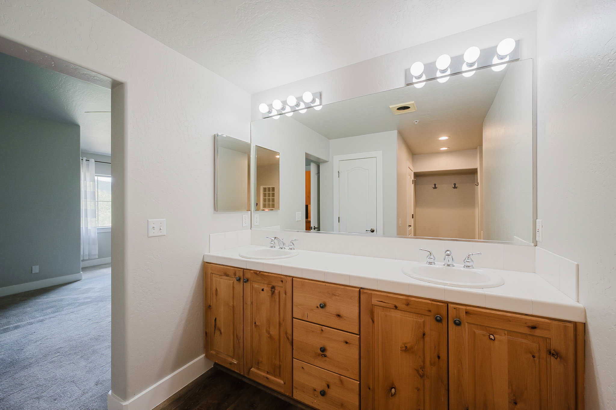 Double vanity featuring wood-finish cabinetry, dual undermount sinks, and a white countertop