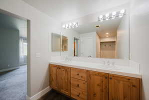 Double vanity featuring wood-finish cabinetry, dual undermount sinks, and a white countertop