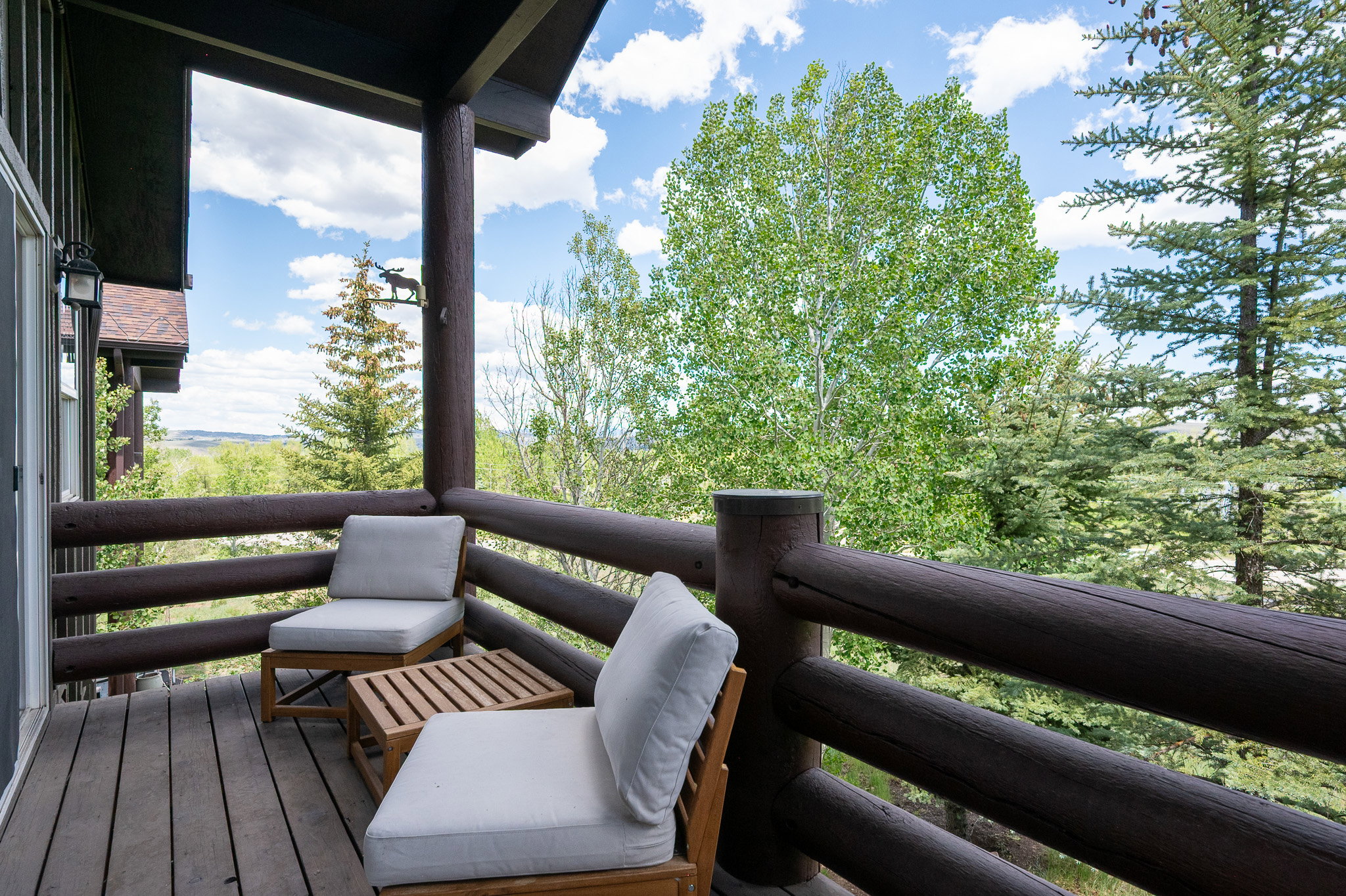 Spacious private balcony featuring robust log railing and natural wood plank flooring