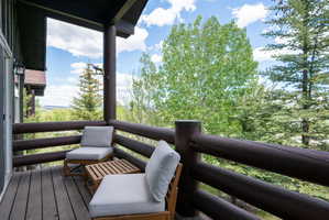 Spacious private balcony featuring robust log railing and natural wood plank flooring
