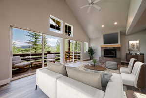 Spacious living area featuring a vaulted ceiling and wood-finish flooring - Virtually staged